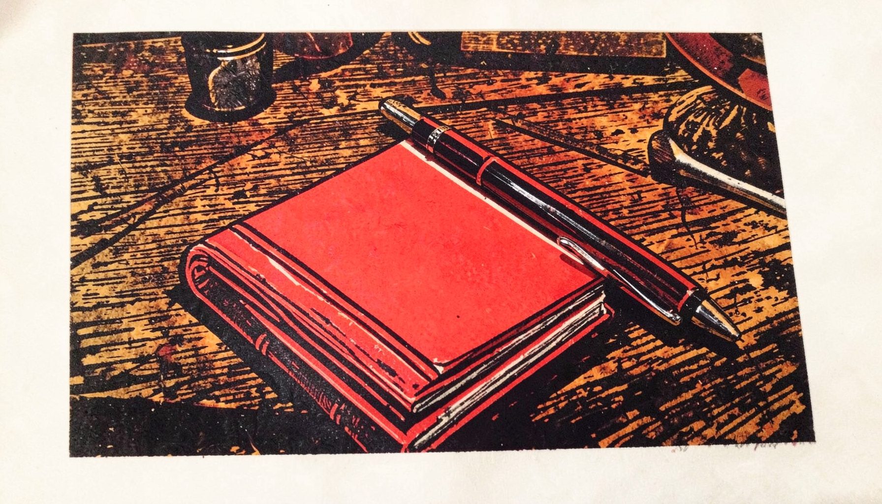 A linocut relief print of a notebook and pen resting on a wooden desk, warm browns and deep charcoal tones, contemplative mood